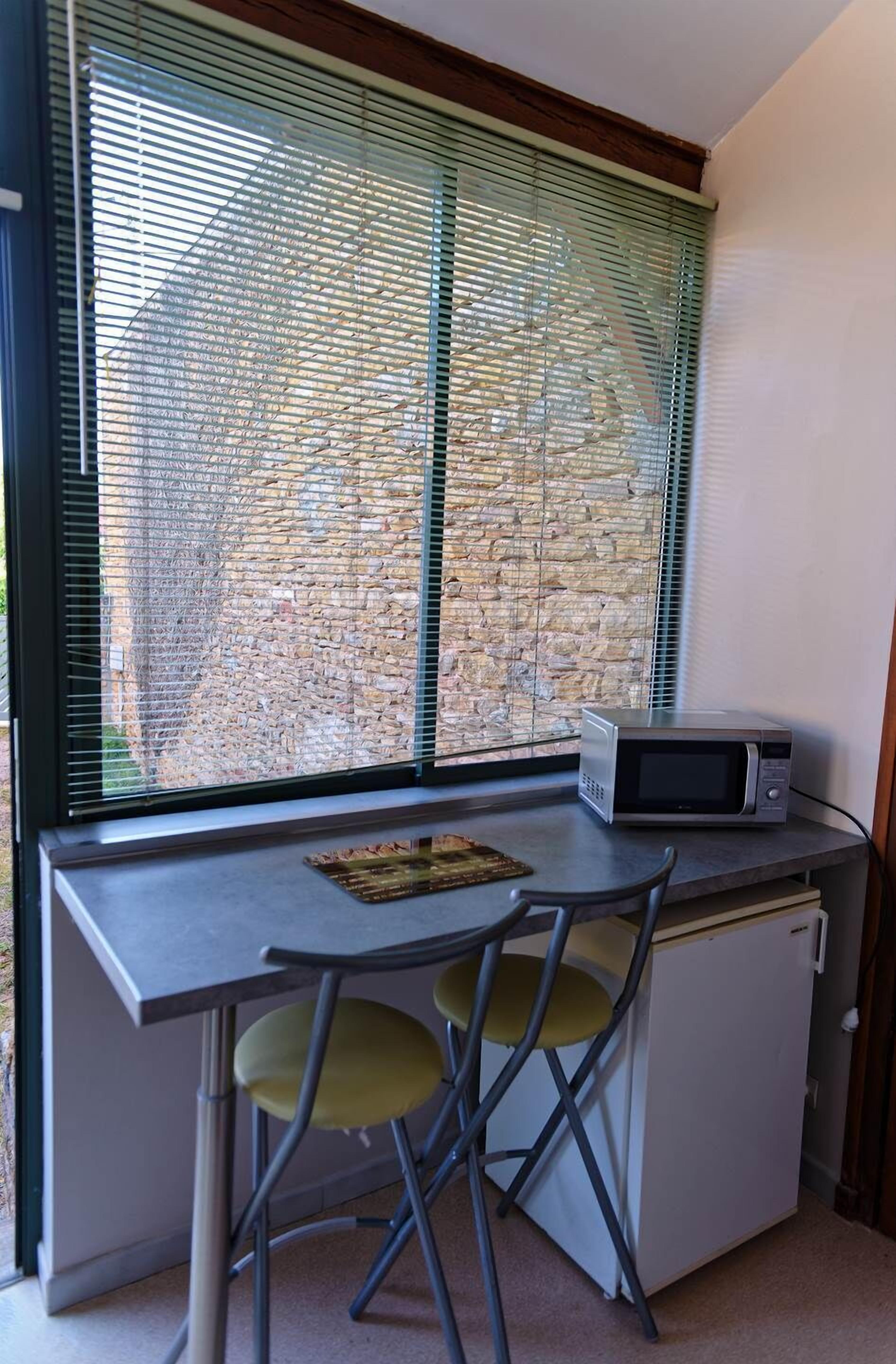 Une petite cuisine équipée d’un four à micro-ondes, d’un petit réfrigérateur et d’un coin repas avec deux chaises.