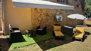 An outdoor seating area with wicker furniture, a white awning, and an air conditioning unit. - My little paradise / private indoor pool (Lournand)