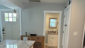 A kitchen with a granite countertop, wooden cabinets, a wicker basket, and a window above the sink.
