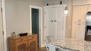 A modern kitchen with a central island, white cabinetry, and a wicker sideboard.