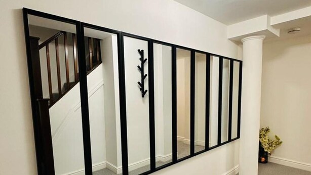 A hallway with a large mirror, a staircase, and a white column. - Home Away From Home- City Centre Gem (Derby)