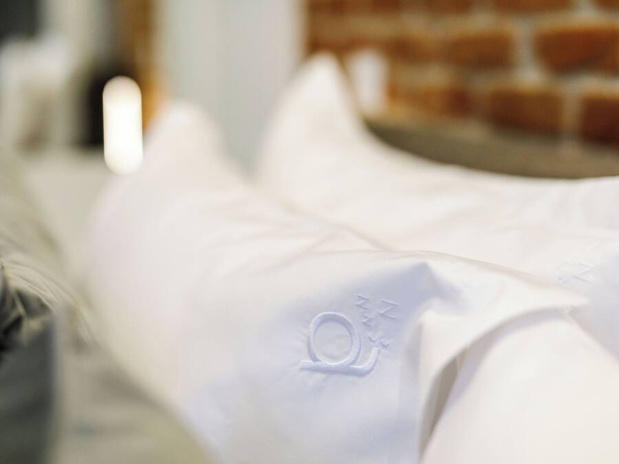 A close-up of a white pillow with an embroidered logo.