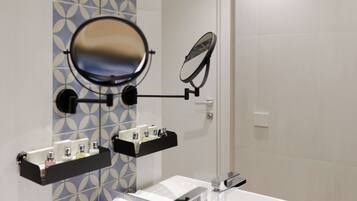 A bathroom with a mirror, a towel rack, and a shelf with toiletries.