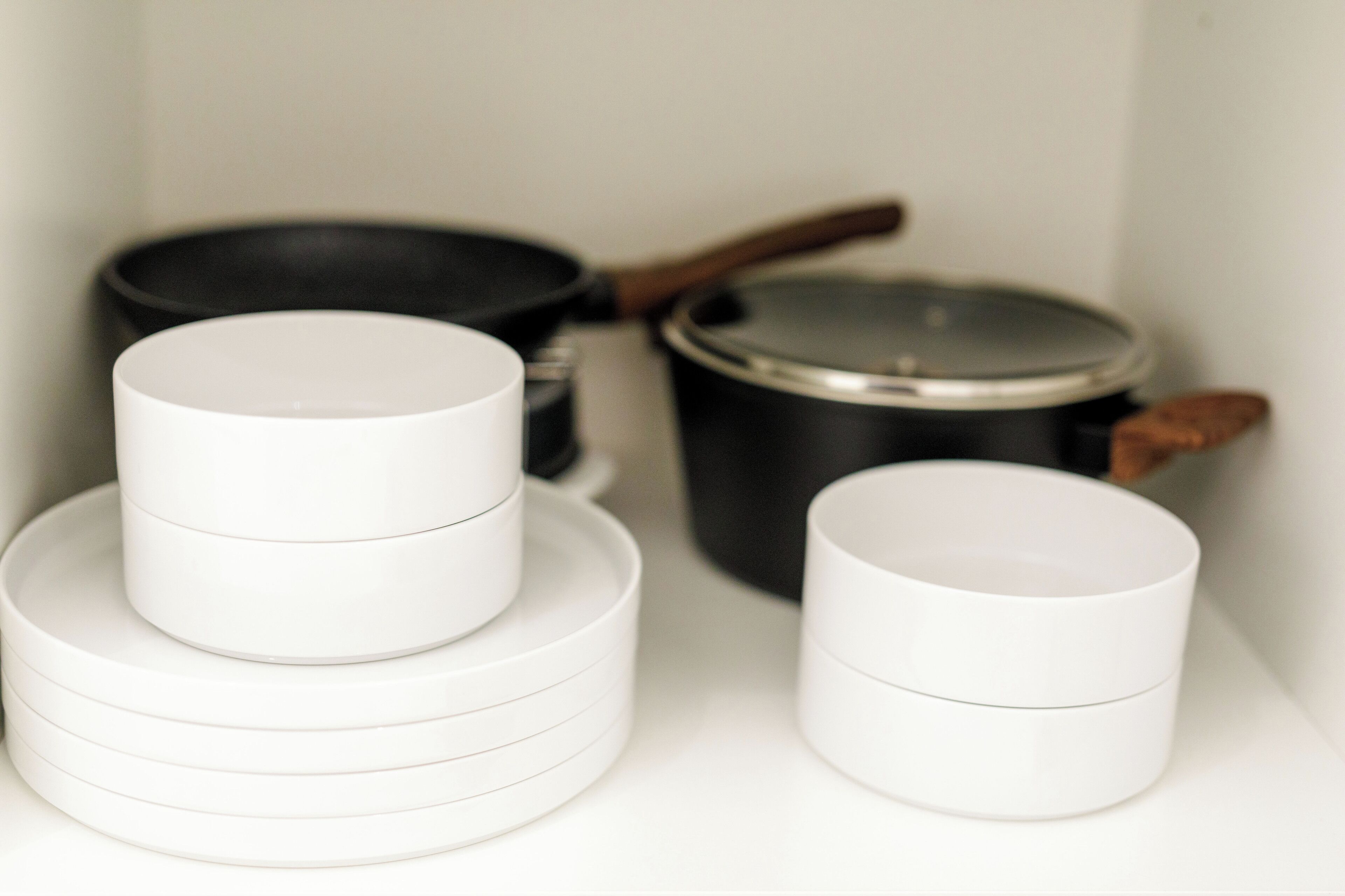 A kitchen with white and black cookware, including a frying pan and a pot with a lid.