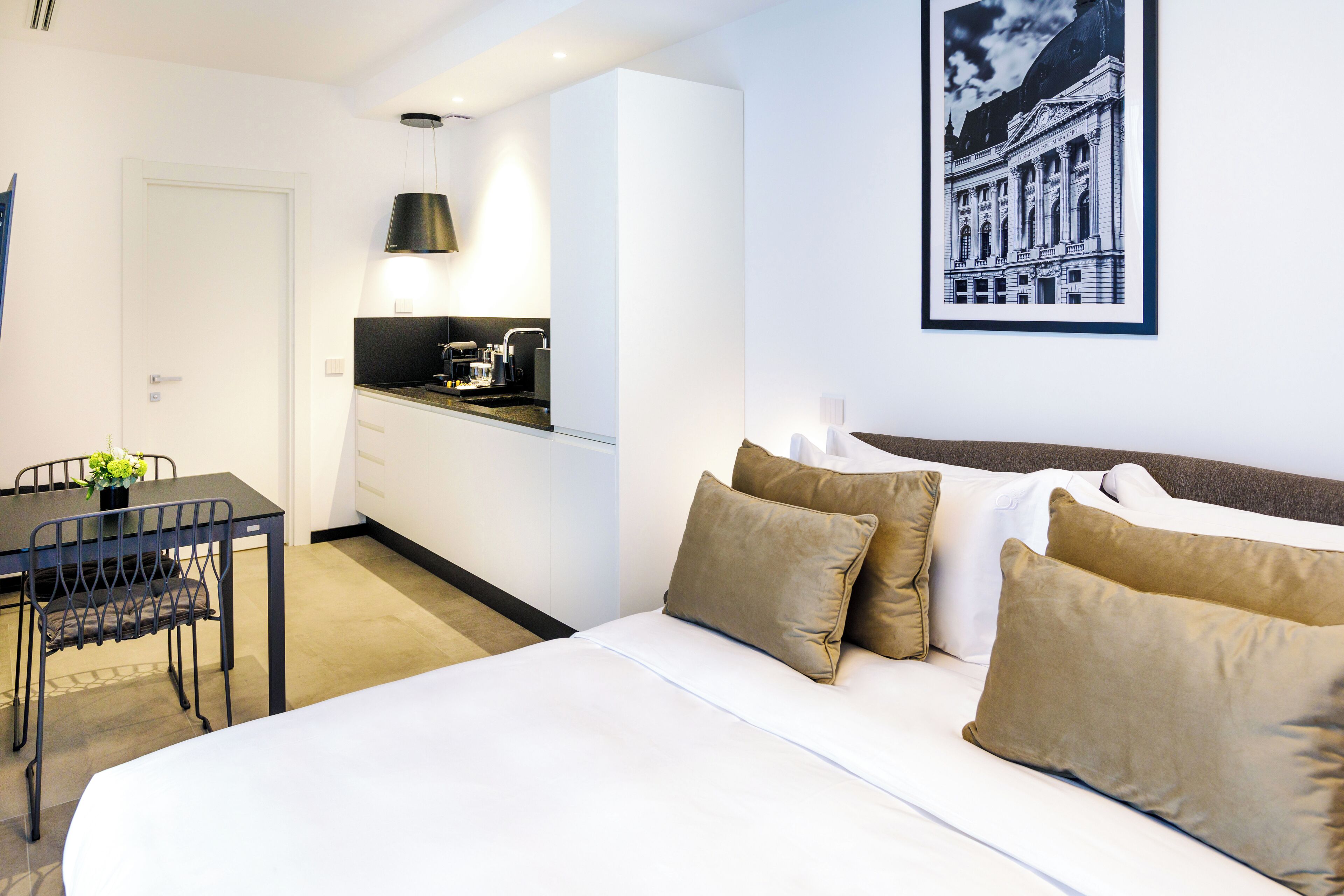A hotel room with a bed, a dining table, a chair, and a kitchenette.