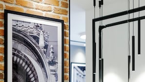 A modern living room with a brick wall, a framed black and white photo, a white sofa, and a minimalist light fixture. - OLD TOWN SNAIL Design Apartments (Bucharest)