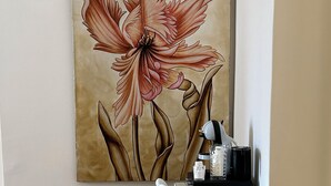 A dining area with a table set for two, a coffee machine, and a decorative painting of a flower on the wall. - Home To Salerno B&B (Salerno)