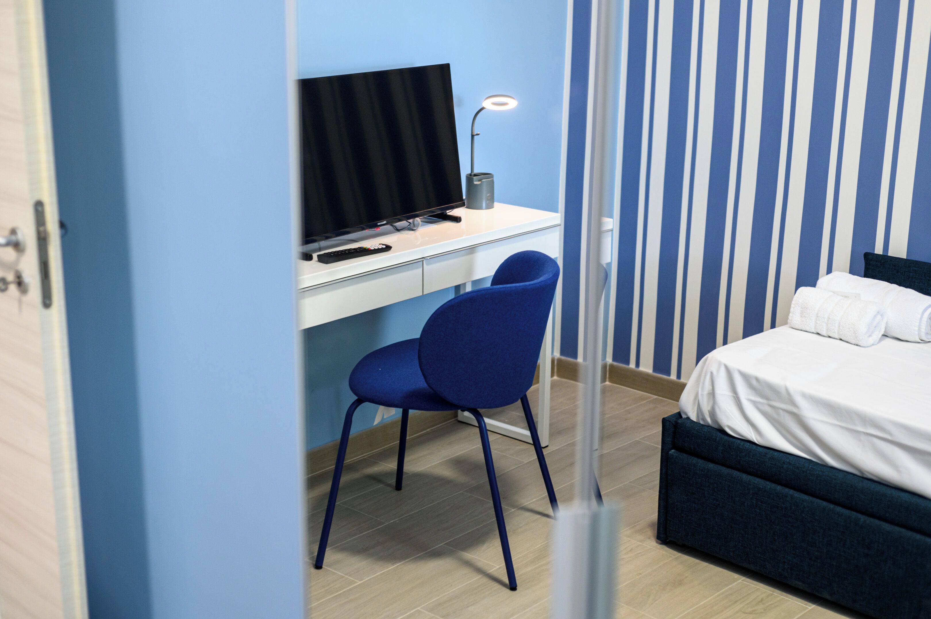 Una habitación con una cama, un escritorio con computadora y una silla.