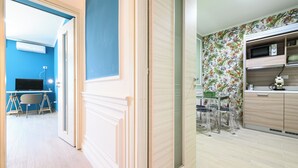 A modern kitchen with a microwave, cabinets, and a dining area with chairs. - Via Nuova Marina 121 - Appartamento 1 (Naples)