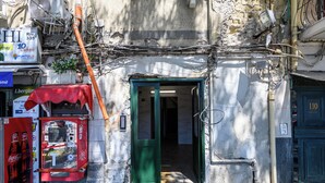 Une étroite entrée menant à un bâtiment avec une porte verte, un distributeur automatique de Coca-Cola et une enseigne indiquant un point de vente de loterie.