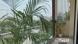 A balcony with a potted plant and a view of the city. - Lime Tree Hotel Golf Course Extension Rd (Gurugram)