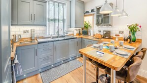 A modern kitchen with grey cabinets, a wooden countertop, and a dining area with a wooden table and chairs. - 3 bedroom accommodation in Pickering (Pickering)