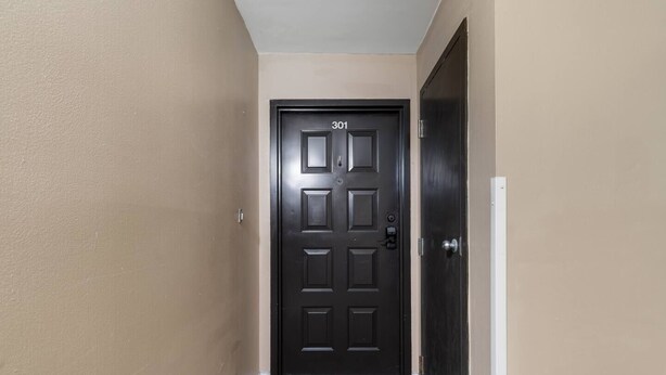 Un pasillo con una puerta negra marcada '301' y una puerta blanca a la derecha.