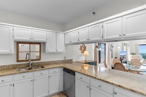 A modern kitchen with white cabinets, granite countertops, and a built-in dishwasher. - 3 Bdrm @ Sea marsh II-pool- corner oceanfront view (North Myrtle Beach)