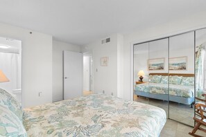 Une chambre à coucher avec un lit, un miroir, une table de chevet et une chaise en bois.