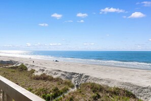 A beach with a clear sky, a sandy shore, and a few people in the distance. - 3 Bdrm @ Sea Marsh II-Pool- Corner Oceanfront View (North Myrtle Beach)