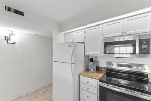 A modern kitchen with white cabinets, a stainless steel refrigerator, a microwave, and an oven. - 3 Bdrm @ Sea marsh II-pool- corner oceanfront view (North Myrtle Beach)