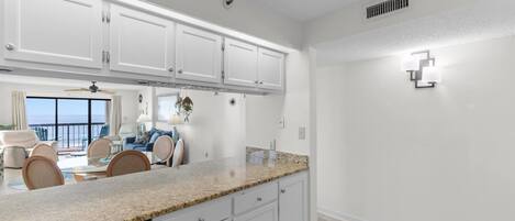 A kitchen with white cabinets, a granite countertop, and a dishwasher.