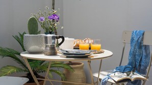 A small round table with a coffee pot, plates, glasses, and a vase with flowers.