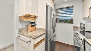 A kitchen with a stainless steel refrigerator, a microwave, and an oven. - Royal Mauian 503-Oceanfront with AC (Kihei)