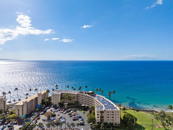 A hotel with a curved building, a parking lot, and a view of the ocean.