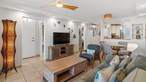 A modern living room with a flat-screen TV, wooden coffee table, and a sofa. - Royal Mauian 503-Oceanfront with AC (Kihei)