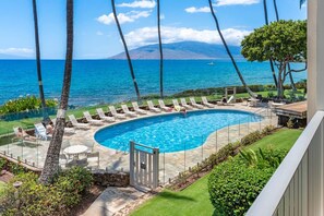 A swimming pool with lounge chairs and a view of the ocean.