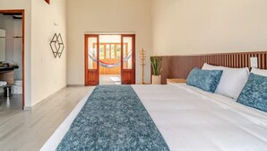 A bedroom with a large bed, a wooden headboard, a hammock, and a view of the outdoors through a door. - Villa Santa Ana Premium (Villa de Leyva)