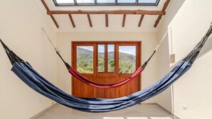 A hammock in a room with a wooden door and windows overlooking a landscape. - Villa Santa Ana Premium (Villa de Leyva)
