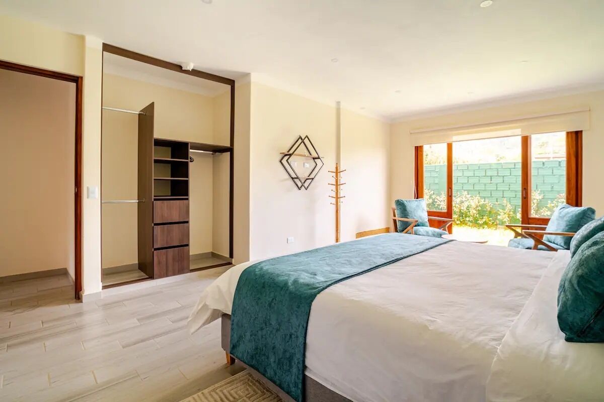 Un dormitorio con cama, armario, silla y ventana con vista a zonas verdes.