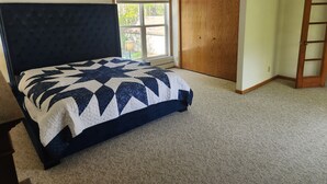 Un dormitorio con una cama grande, una ventana con persianas, un armario de madera y una puerta.