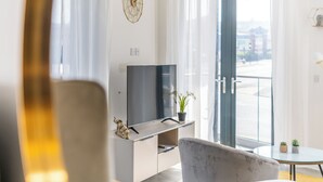 Una habitación de hotel moderna con cama, televisión, una mesita y un balcón con vistas.