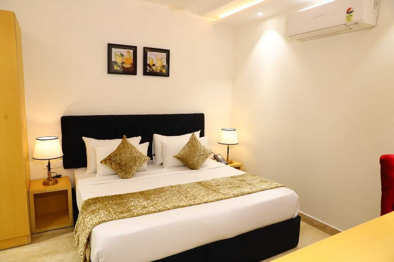 A hotel room with a large bed, two bedside lamps, a red chair, and two framed pictures on the wall.