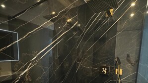 A modern bathroom with black marble walls, a glass shower enclosure, and a visible control panel. - Modern Green & White - Apartment T3 60m2 Annecy - Parking Privé - Wifi - Netflix (Annecy)