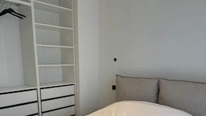 A bedroom with a bed, a wardrobe, and a nightstand. - Modern Green & White - Apartment T3 60m2 Annecy - Parking Privé - Wifi - Netflix (Annecy)