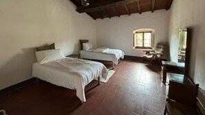Een kamer met twee bedden, een raam, een stoel en een tafel.