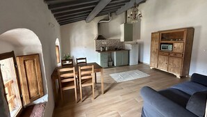 Een ruime woonkamer met een houten eettafel, een blauwe bank en een keuken op de achtergrond.