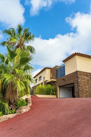 A modern house with a red driveway, a palm tree, and a clear blue sky. - Résidence Esterel 1, Villa Pour 12 Personnes Avec Accès 5 à Esterel Caravaning (Saint-Raphaël)