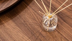 Uma mesa de madeira redonda com um castiçal de vidro contendo uma vela acesa e incensos.