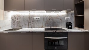 Cozinha moderna com painel de fundo em mármore, forno embutido e cafeteira.
