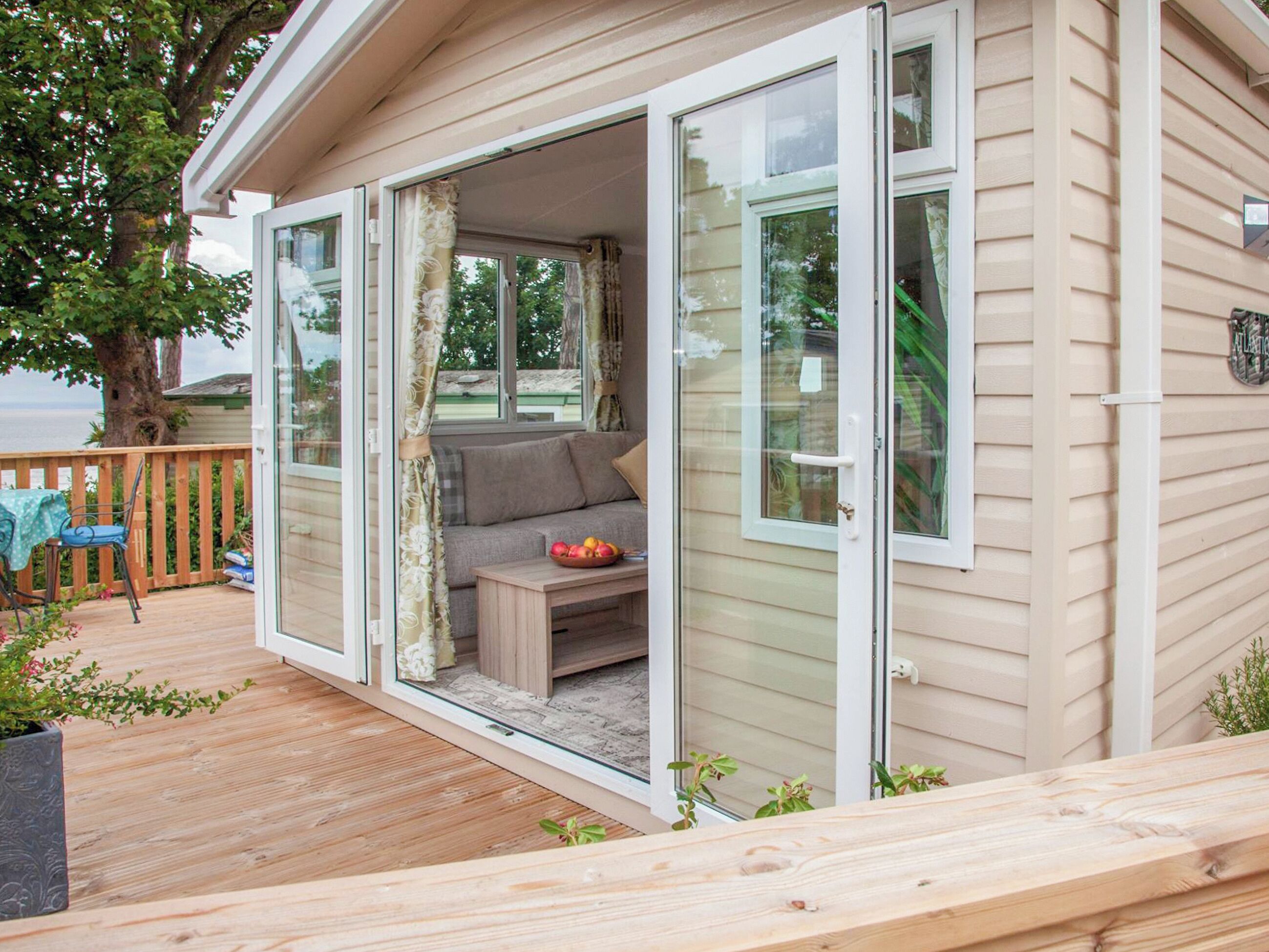 A cozy cabin with a deck, a sofa, and a table with fruit.
