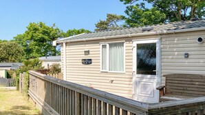 A mobile home with a deck, a window, and a door. - 2 bedroom accommodation in West Quantoxhead, near Watchet (West Quantoxhead, near Watchet)