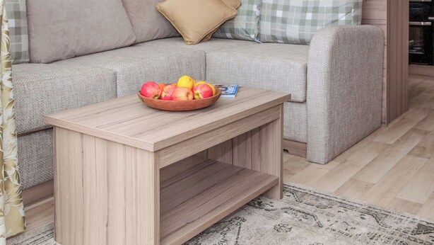 A modern living room with a sofa, a small wooden table with a bowl of fruit, and a patterned rug. - 2 bedroom accommodation in West Quantoxhead, near Watchet (West Quantoxhead, near Watchet)