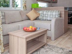 Una sala moderna con un sofá, una mesita de madera con un frutero y una alfombra estampada.