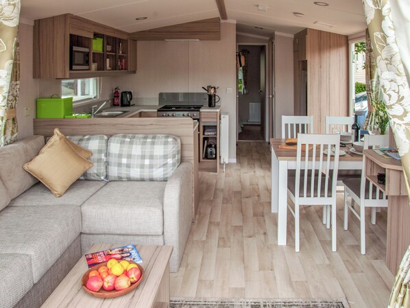 Un espacio habitable compacto con kitchenette, comedor y sofá con cojines.