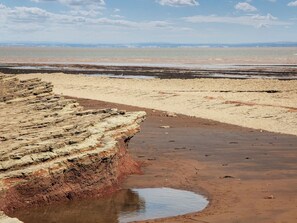 Un paisaje costero con formaciones rocosas estratificadas y una playa arenosa.