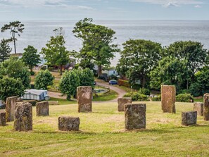 Un cementerio con lápidas de piedra, árboles y un camino que lleva a una casa.