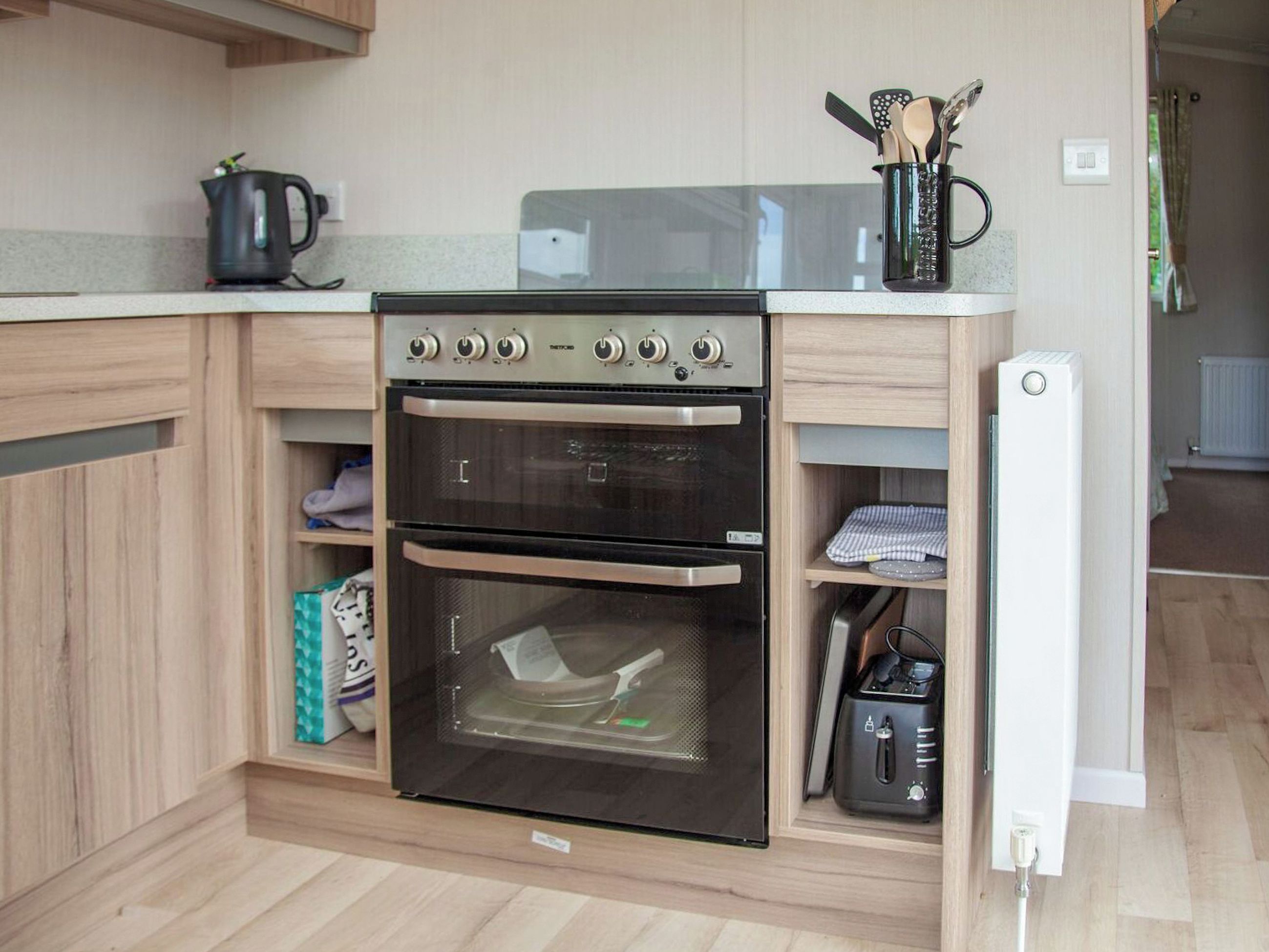 A compact kitchen with a built-in oven, a kettle, and a toaster.