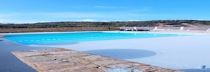 A swimming pool with clear blue water, surrounded by a white deck and stone walls. - Appartement a Louer au Nord du Maroc Fnideq (Fnideq)