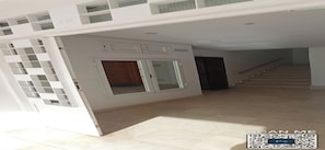 A spacious interior with a staircase leading to an upper level, a large open door, and a modern design with white walls and a tiled floor. - Appartement a Louer au Nord du Maroc Fnideq (Fnideq)